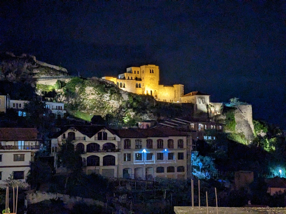 Forteresse historique illuminée sur une colline la nuit.