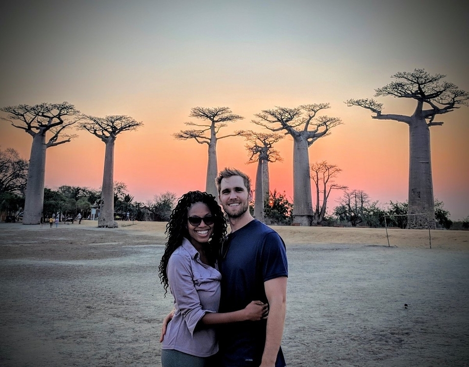 Couple devant des baobabs au coucher du soleil.