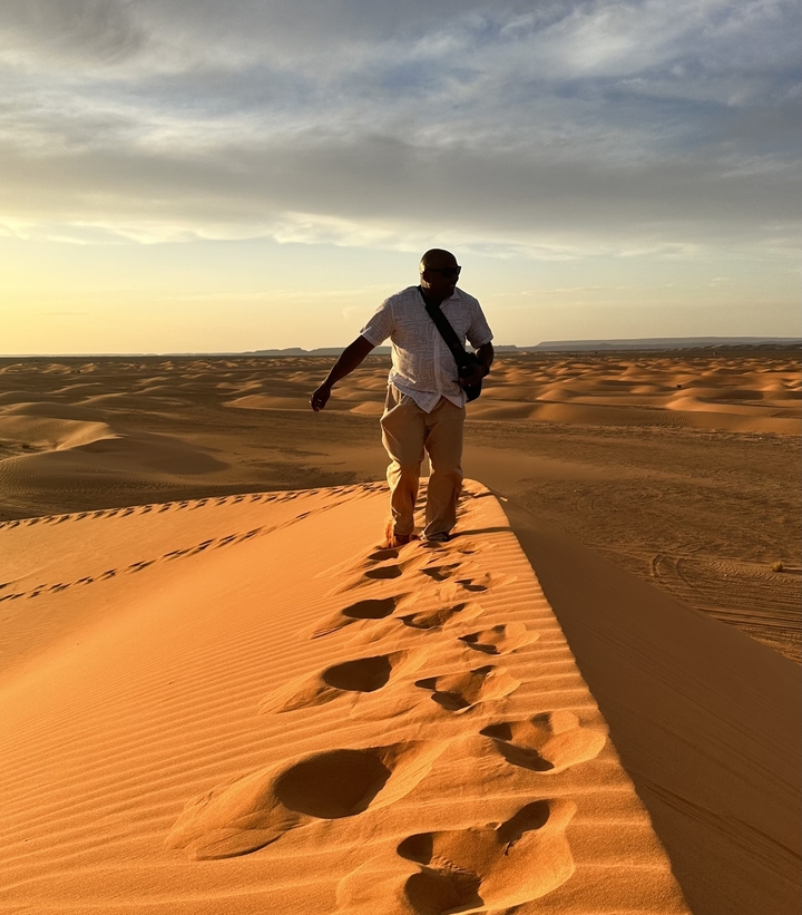 Personne marchant sur les dunes de sable au coucher du soleil.