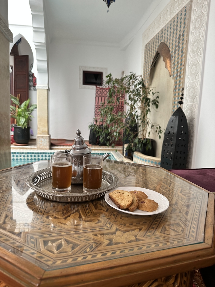 Service à thé marocain avec des biscuits sur une table au bord d'une piscine.