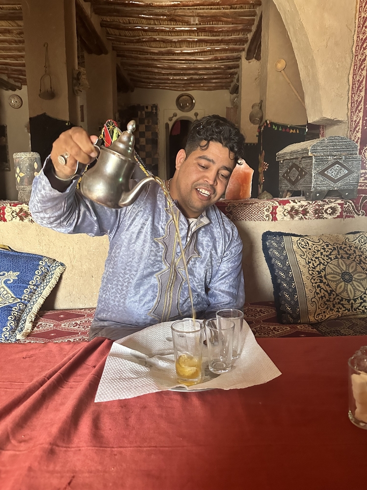 Homme versant du thé dans un cadre traditionnel avec une décoration élégante.