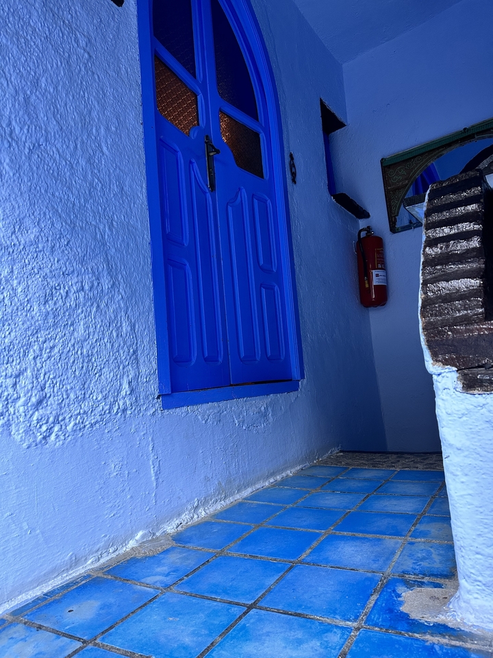 Volet en bois bleu sur un mur dans un coin faiblement éclairé.
