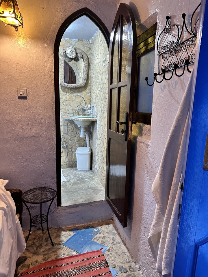 Lavabo de salle de bain rustique vu à travers une porte ouverte.