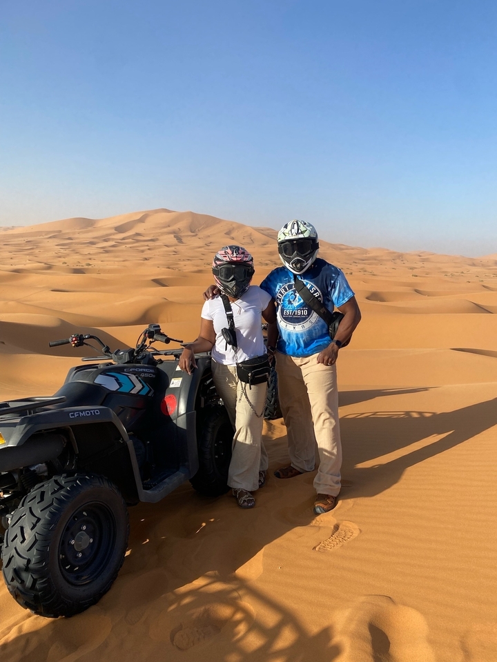 Deux personnes posant avec des vélos sur des dunes de sable.