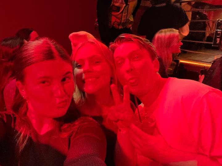 Groupe de personnes posant dans une pièce éclairée en rouge.