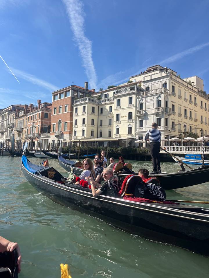 Gondole avec des personnes sur un canal avec des bâtiments en arrière-plan.