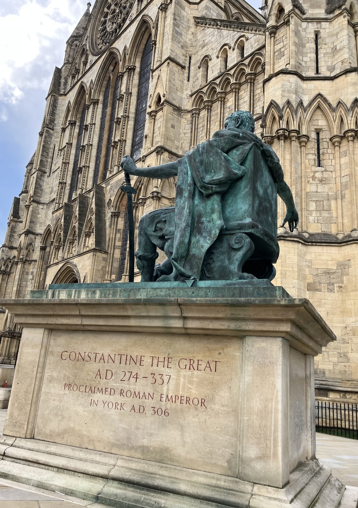 Estatua de una figura histórica sentada fuera de un gran edificio.