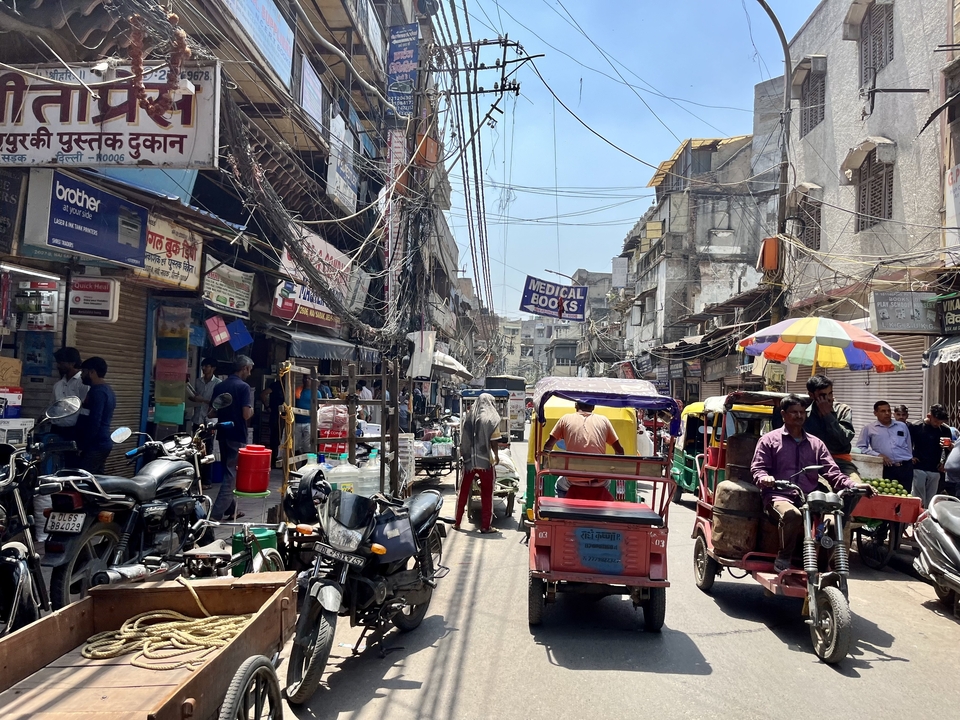 Scène de rue animée avec des tuk-tuks et un marché