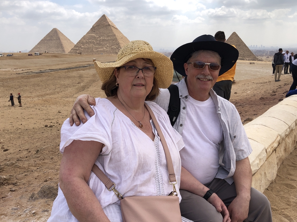Couple posant avec les pyramides en arrière-plan.