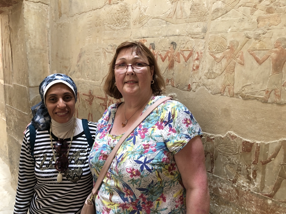 Deux personnes posant devant des sculptures anciennes.