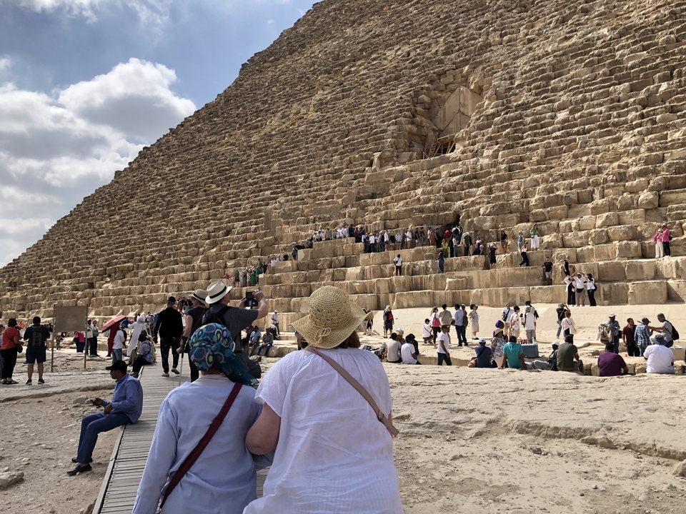 Foule au pied d'une pyramide massive.