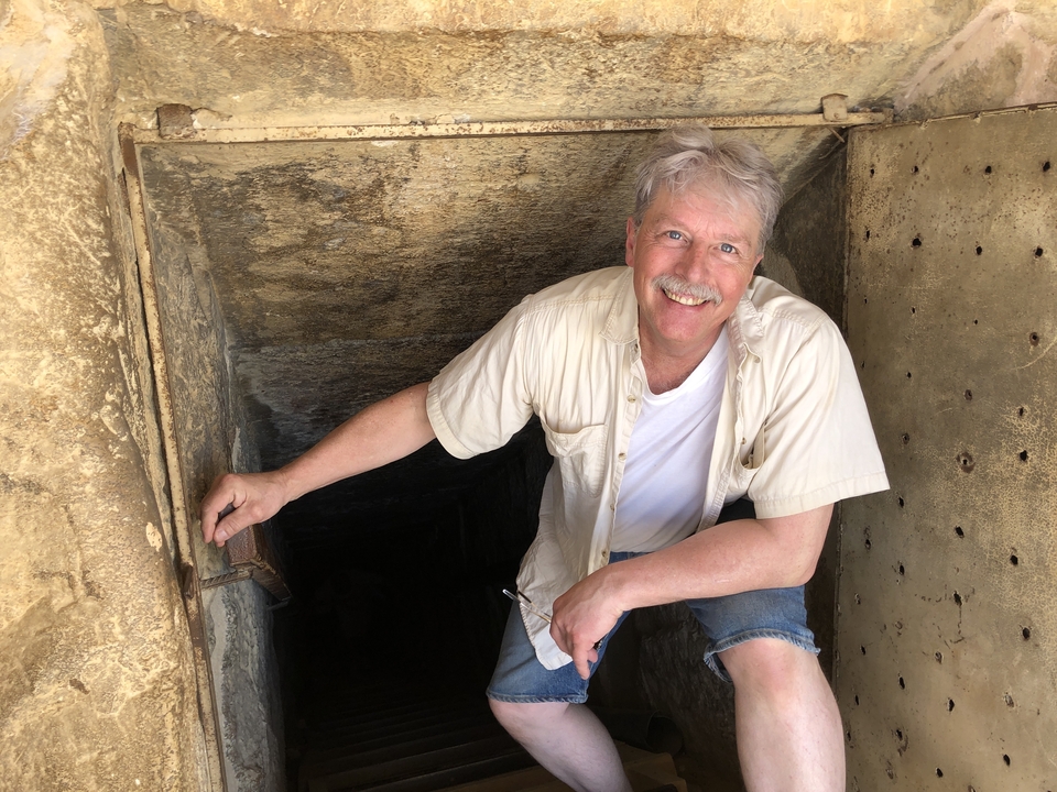 Homme sortant d'une petite entrée dans une ruine.