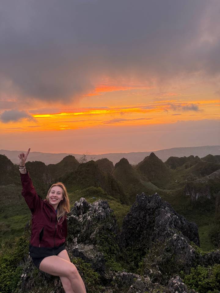Femme posant sur une montagne au coucher du soleil.
