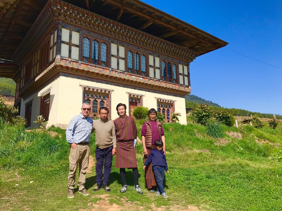 Groupe de personnes debout devant une maison traditionnelle.