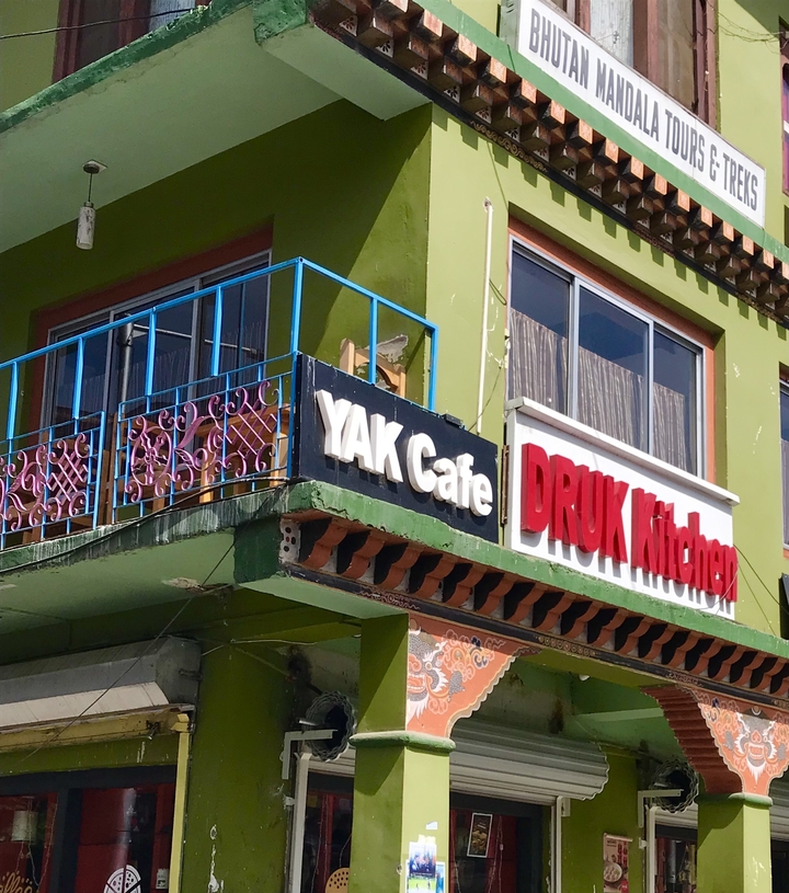 Extérieur d'un bâtiment avec les enseignes Yak Cafe et Druk Kitchen.