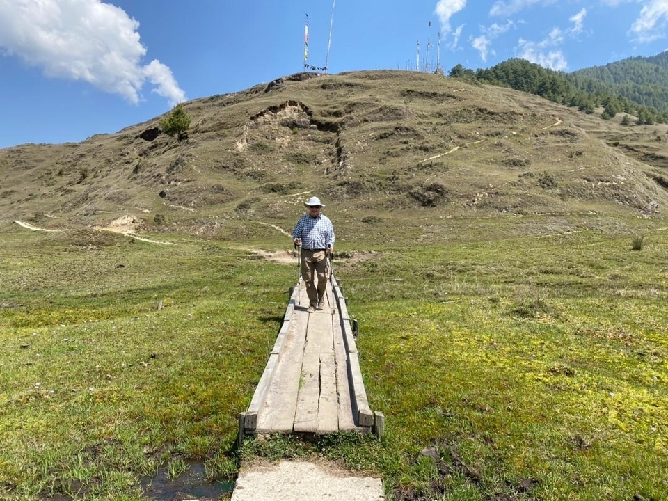 Homme marchant sur un sentier en bois à travers un champ.