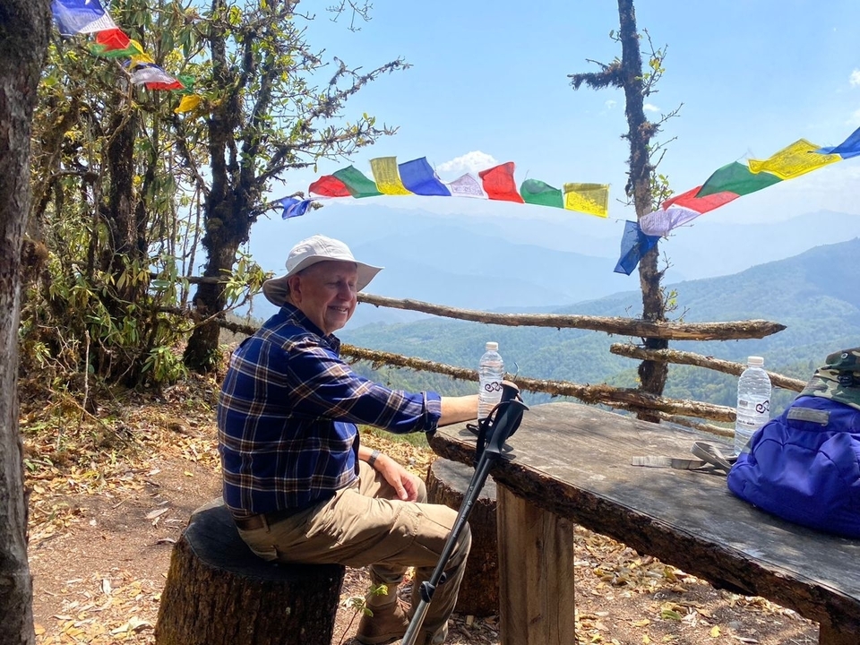 Homme assis à côté de drapeaux de prière avec vue sur les montagnes.