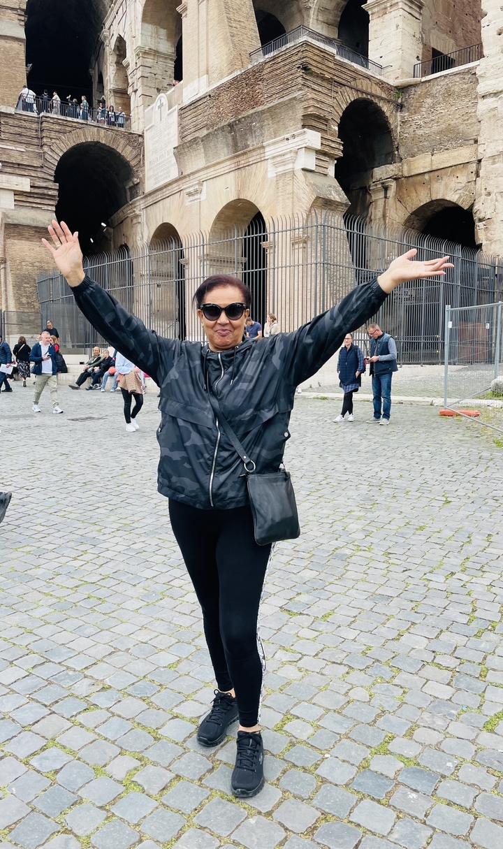 Touriste posant avec enthousiasme devant un bâtiment historique.