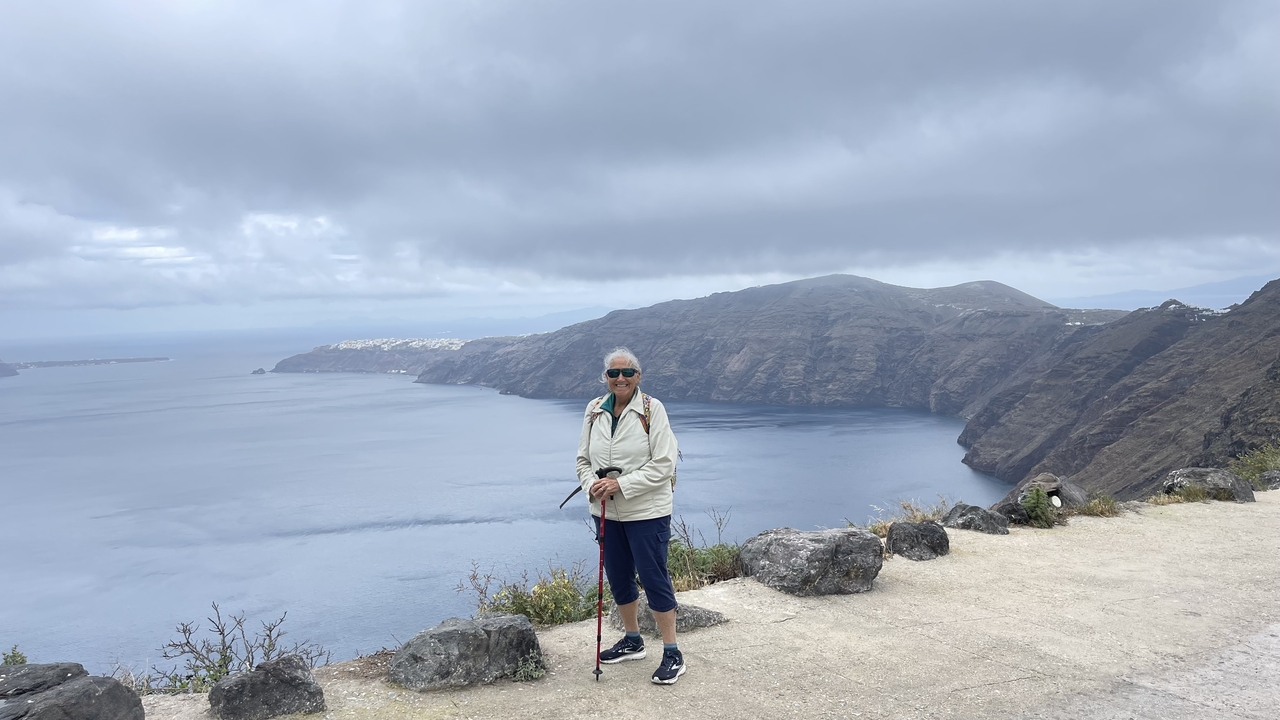 Femme debout sur une falaise avec une vue sur la caldeira de Santorin.