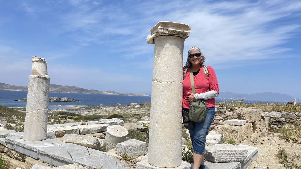 Femme posant à côté de ruines antiques avec vue sur mer à Délos.