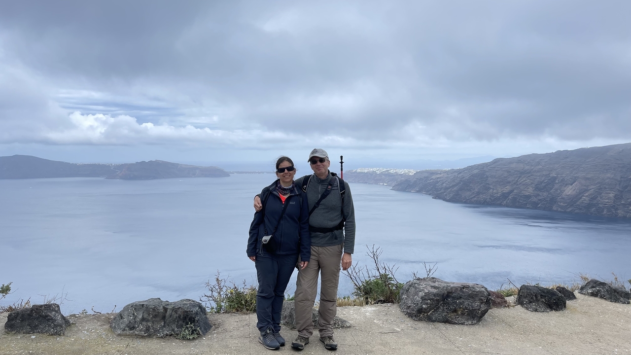 Couple debout sur une falaise surplombant la caldeira de Santorin.