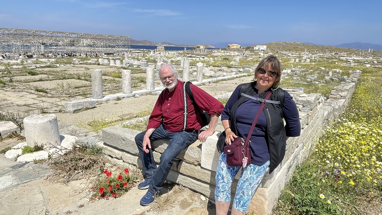 Couple assis sur un rebord de pierre parmi des ruines antiques.