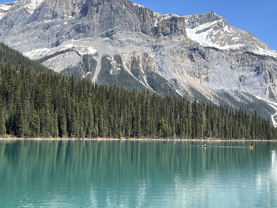 Lac turquoise immaculé entouré d'une forêt de pins et de montagnes.