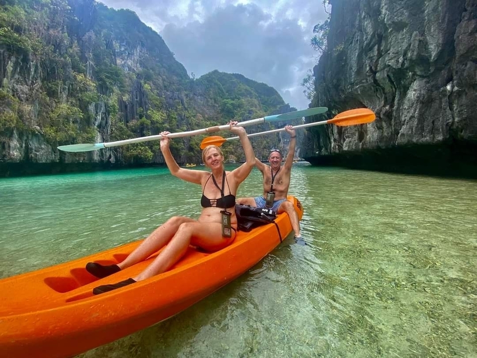 Deux personnes faisant du kayak dans des eaux claires entourées de falaises.