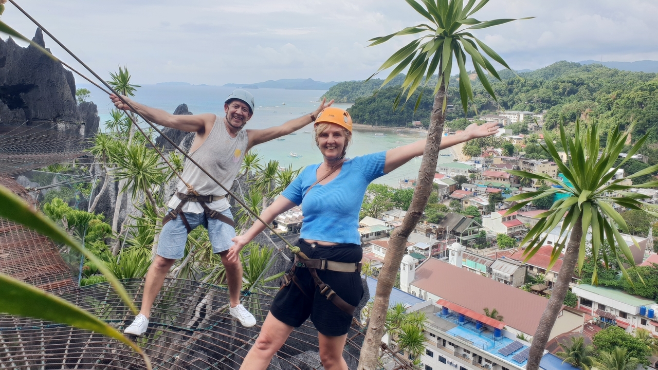 Deux personnes sur une tyrolienne avec une vue panoramique sur la ville et l'océan.