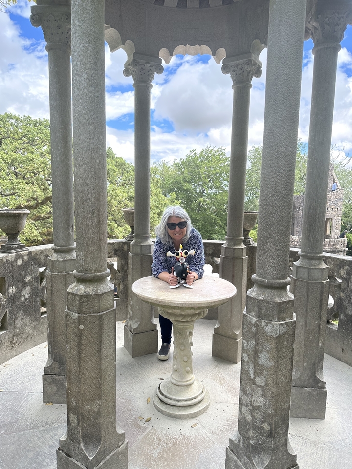 Femme posant avec un ornement de cor jouet entre des piliers de pierre.