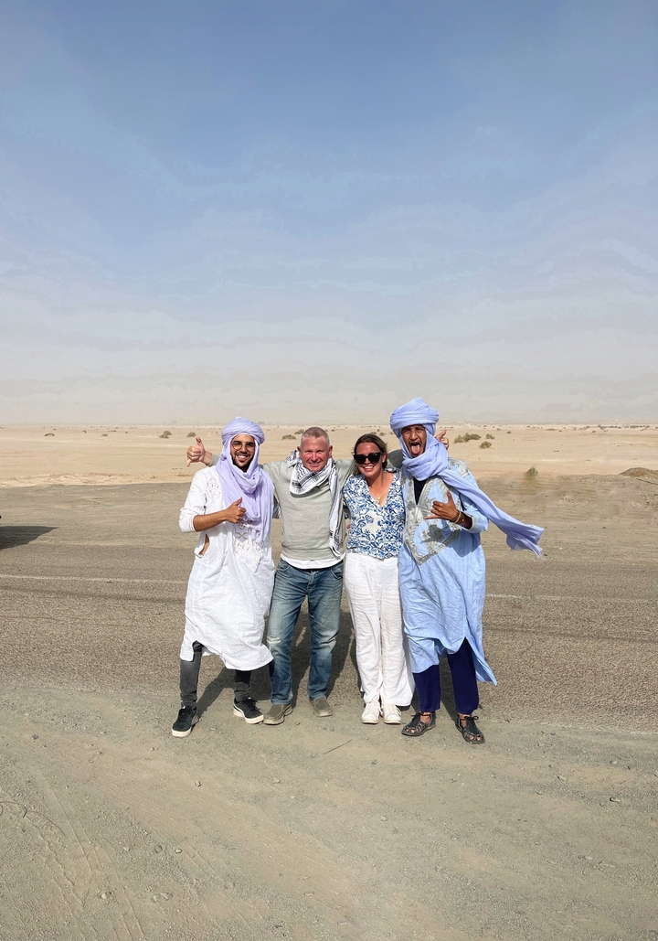 Groupe de personnes posant en tenue traditionnelle dans le désert.