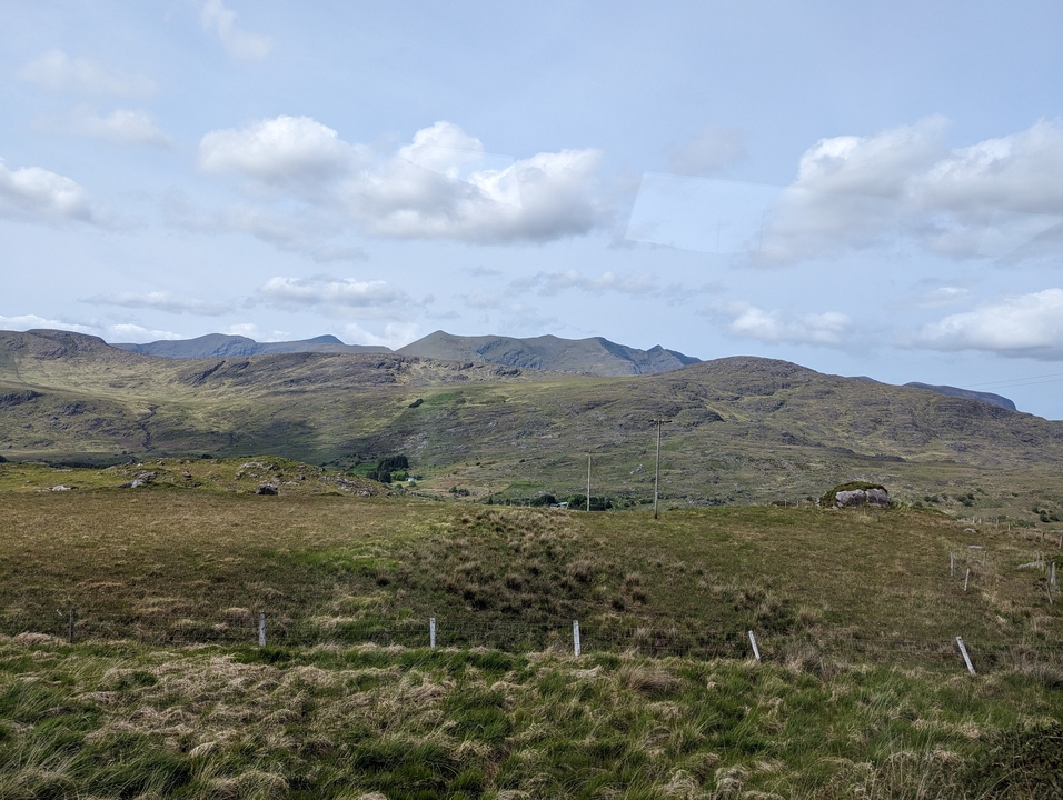 Collines ondulantes et prairies de pâturage sous un ciel nuageux.