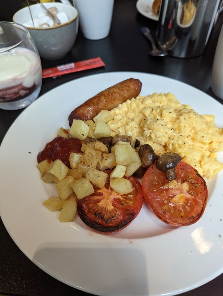 Assiette avec petit-déjeuner comprenant saucisses, pommes de terre et œufs.