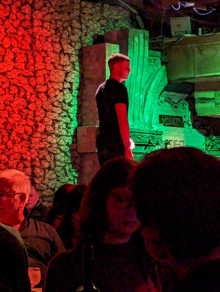 Scène intérieure sombre avec des personnes et un éclairage aux couleurs vives.