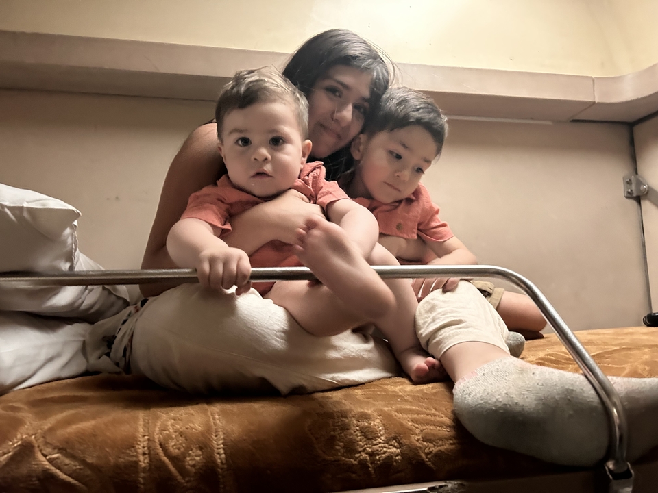 Parent tenant deux jeunes enfants sur un lit.