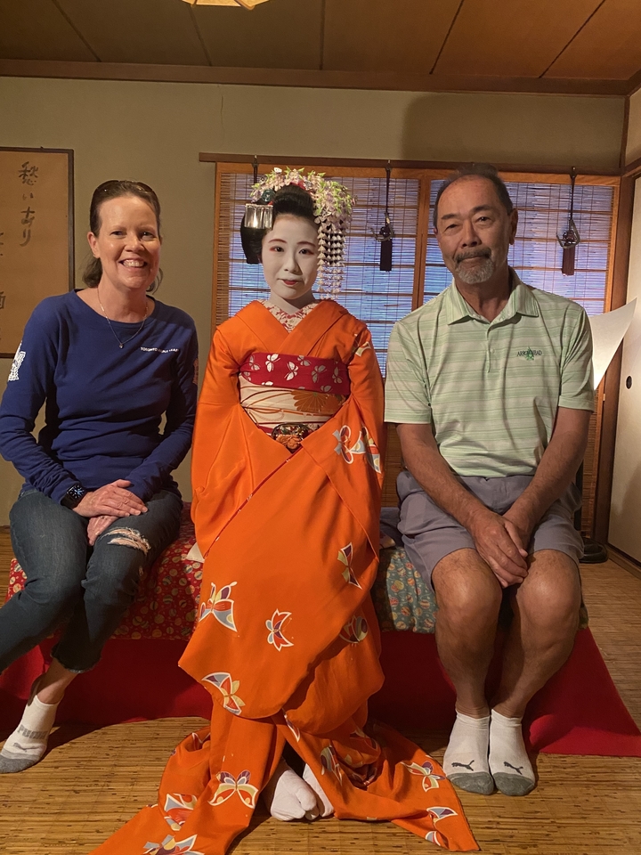 Deux personnes assises avec une femme en tenue japonaise traditionnelle