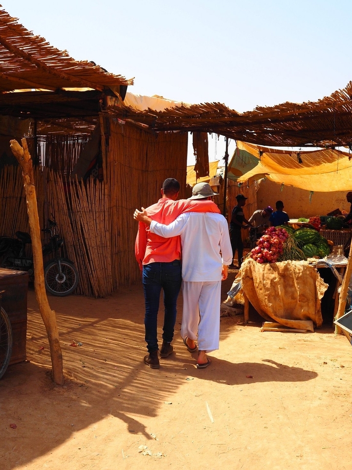 Une scène de marché avec deux personnes marchant bras dessus bras dessous.