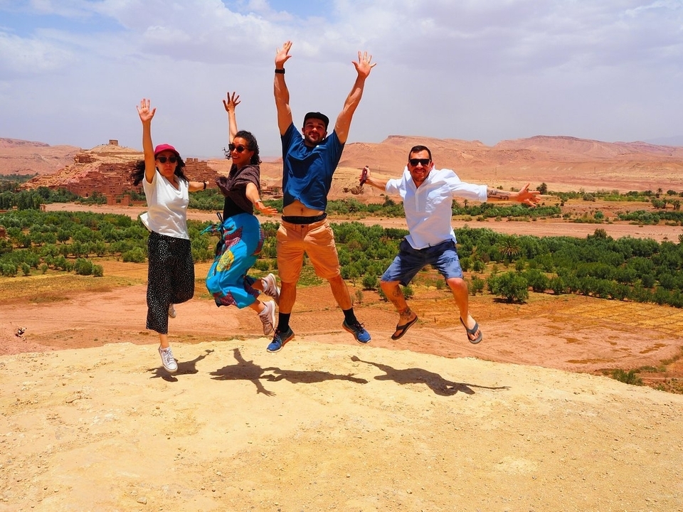 Quatre personnes sautant dans un paysage désertique.