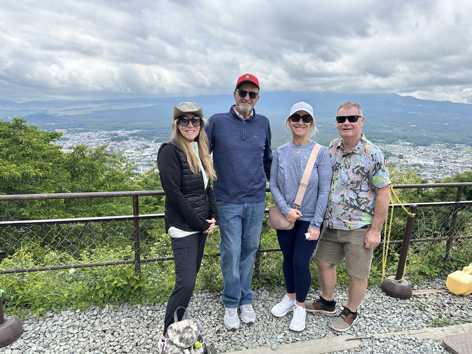 Un groupe de personnes posant avec un paysage de montagne et de ville en arrière-plan.