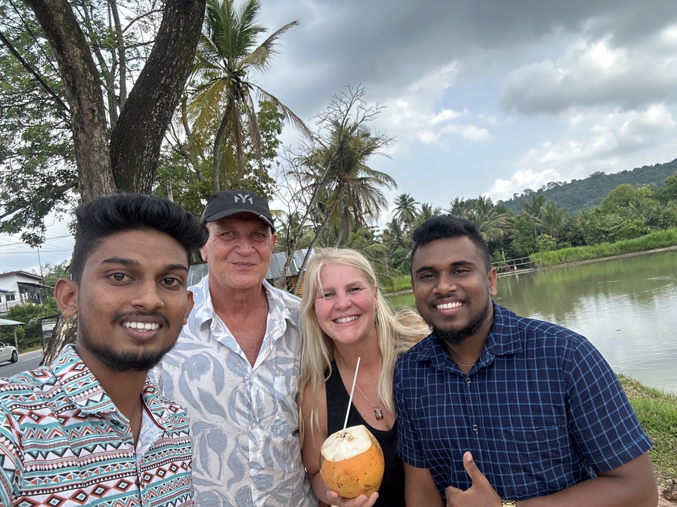 Groupe de personnes souriantes dans un cadre extérieur tropical.