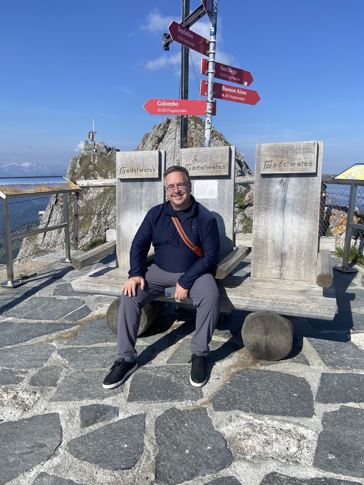 Homme assis sur un grand banc avec vue sur la montagne
