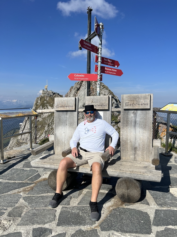 Homme sur de grandes chaises en bois avec un paysage de montagne en arrière-plan