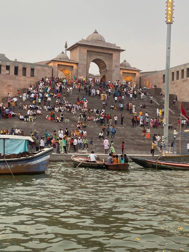 Foule sur les marches du front de rivière avec des bateaux sur l'eau.
