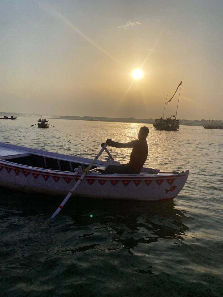 Homme ramant dans un bateau sur une rivière au coucher du soleil.