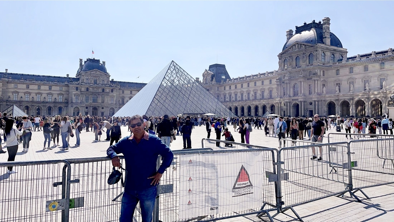 Mann posiert am Louvre-Museum mit seiner Glaspyramide.