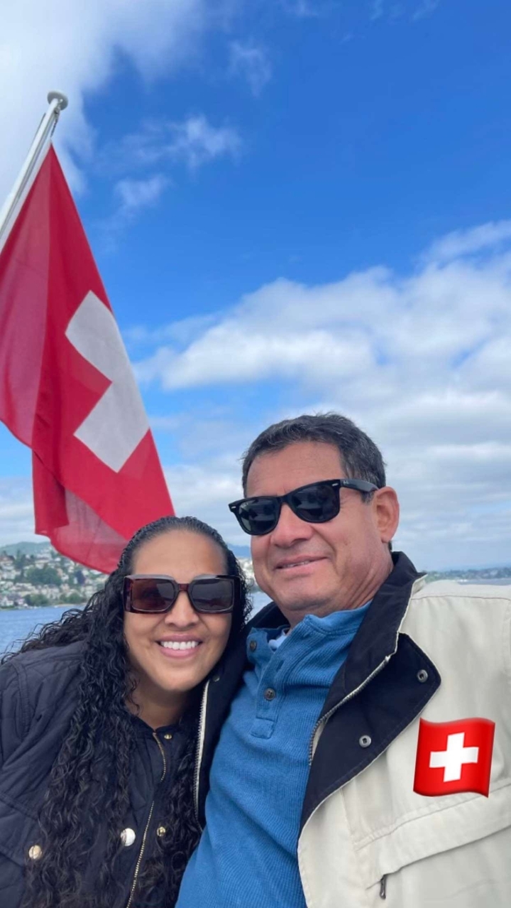 Paar vor einer Schweizer Flagge mit einem See und einer Stadt im Hintergrund.