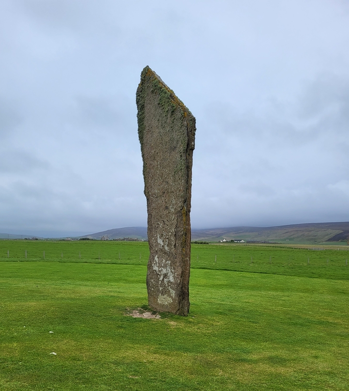 An ancient standing stone on a grassy field.
