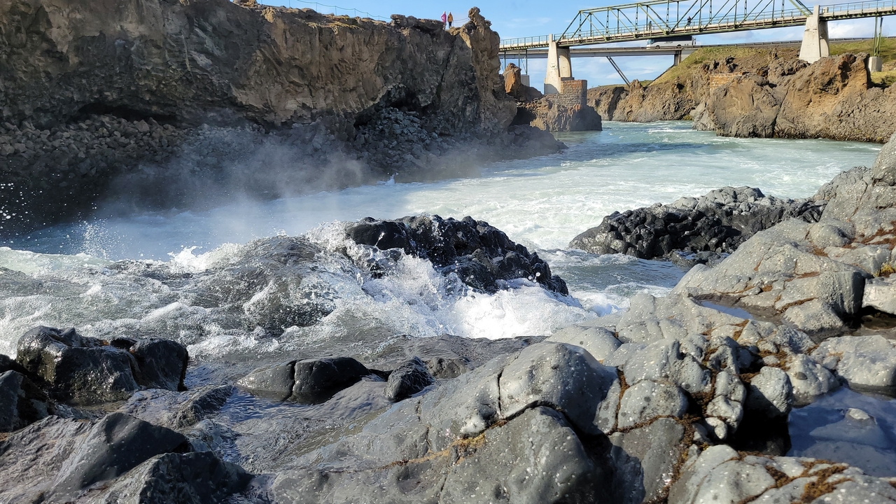 Rough waters with a bridge and rocky banks.