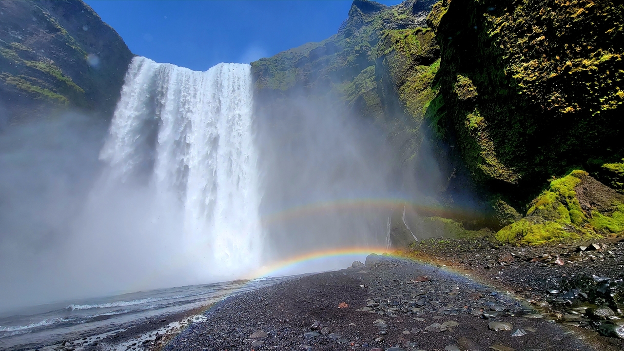 Waterfall with vibrant rainbows at its base.
