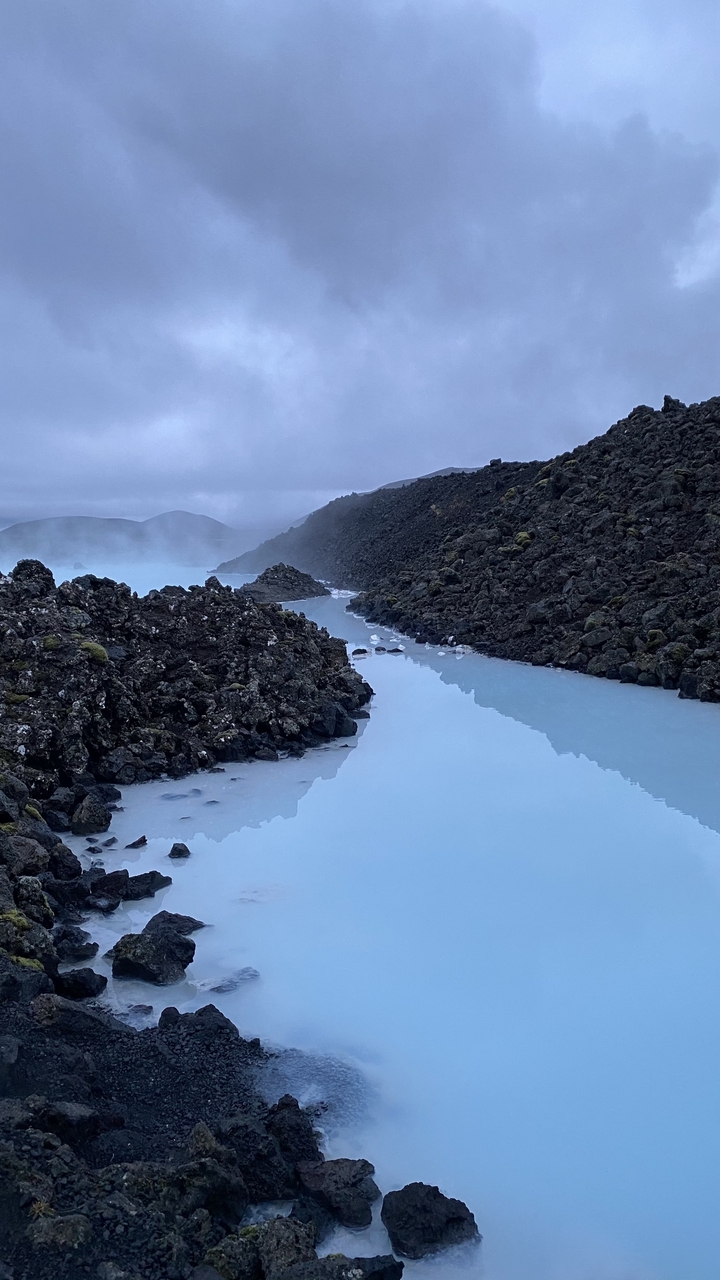 Un paysage serein avec une eau bleu laiteux et des roches de lave